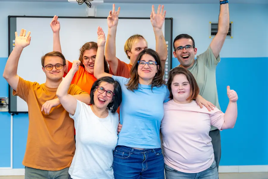 group of young adults with Down syndrome smiling at the camera after a group fitness class
