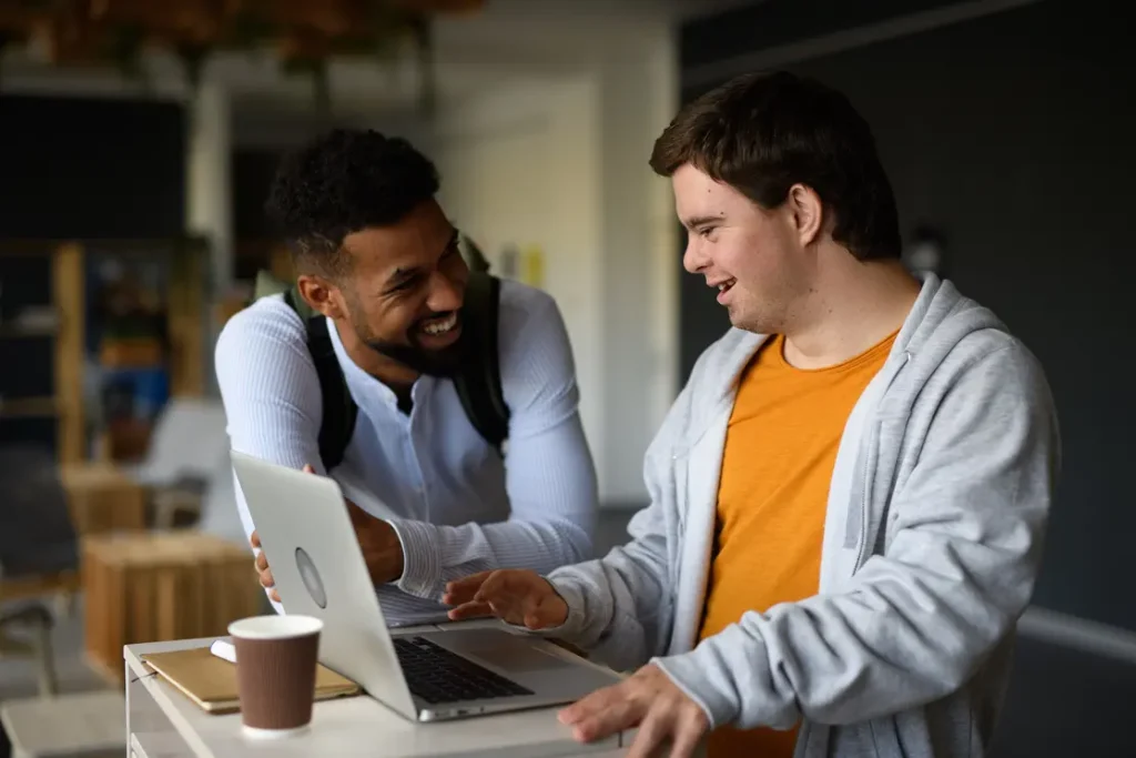 man with Down syndrome and his male support worker using a computer